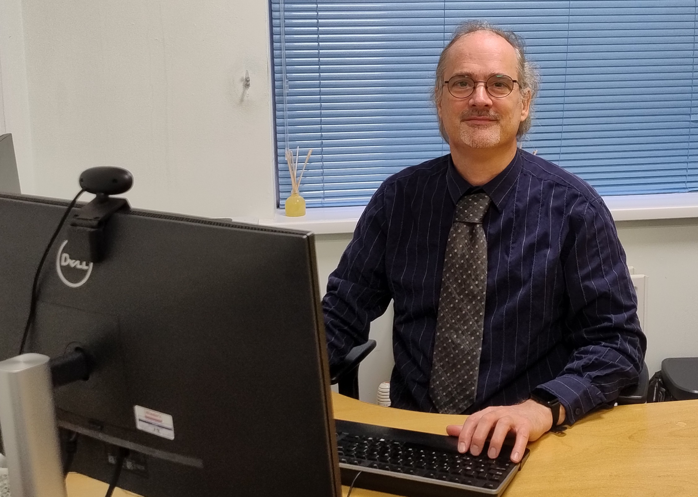 Nigel sits at a desk in front of a computer