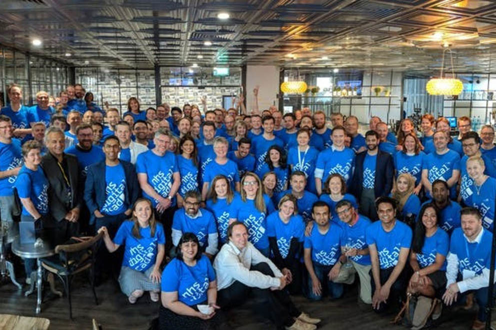 Members of the NHS Digital Academy cohort 1 take part in a group photograph wearing blue t-shirts