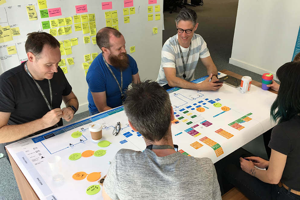team sitting around a large blueprint document