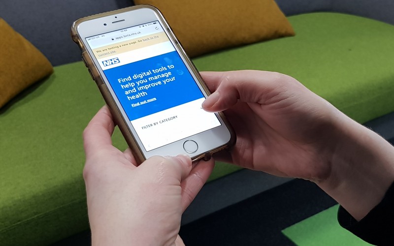 A smartphone in a person's hand with an NHS app open on it.