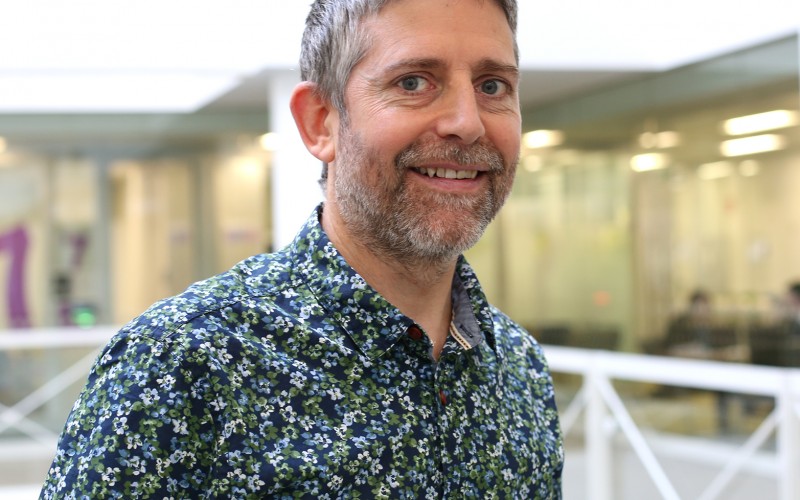 photo of Charles Creswell wearing flowery shirt with corporate atrium background