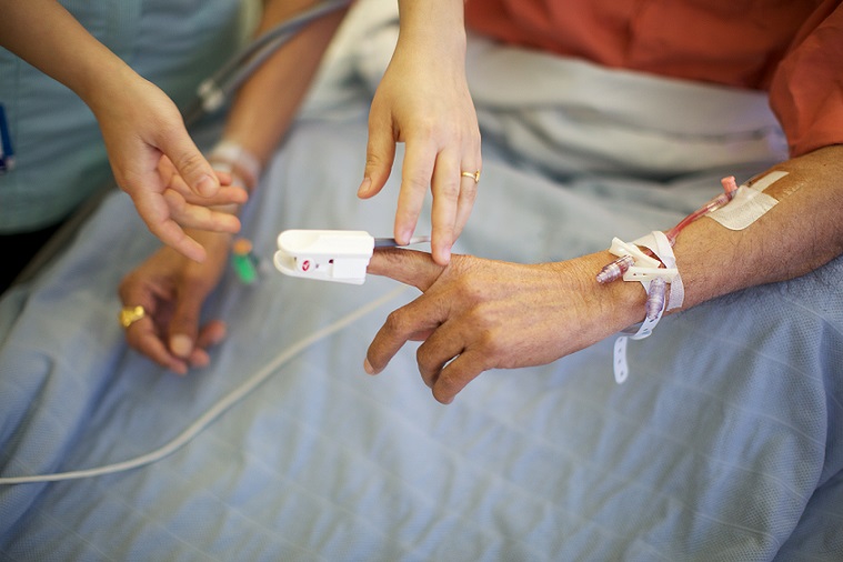 A patient's finger being hooked up to a monitor in a hospital bed