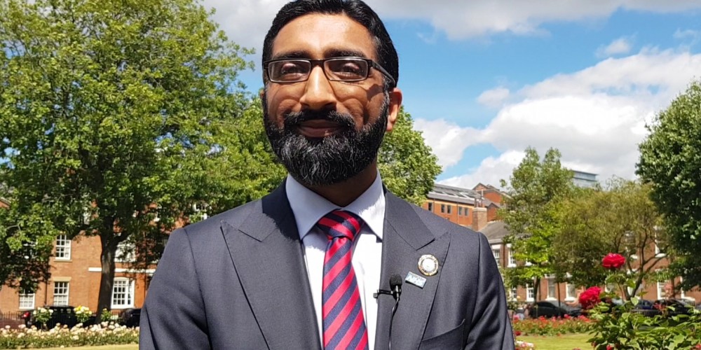 Mohammed Hussain outside dressed in suit and red tie
