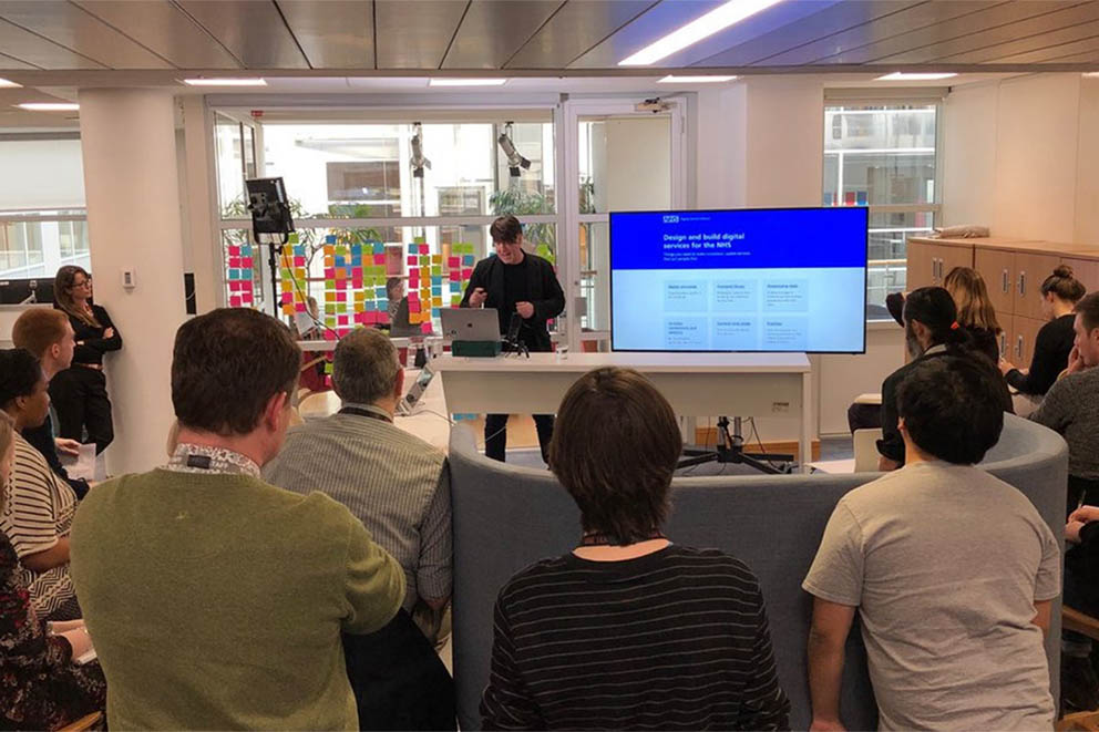 NHS Digital staff look at a wall display full of post-it notes when collaborating on the NHS login